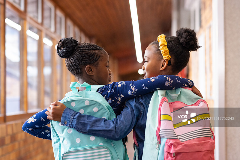 在学校走廊里，两个非裔美国女孩拥抱微笑图片素材