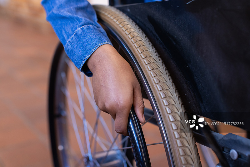 握着轮椅轮子的非洲裔美国女孩独立地在学校走廊里行走图片素材