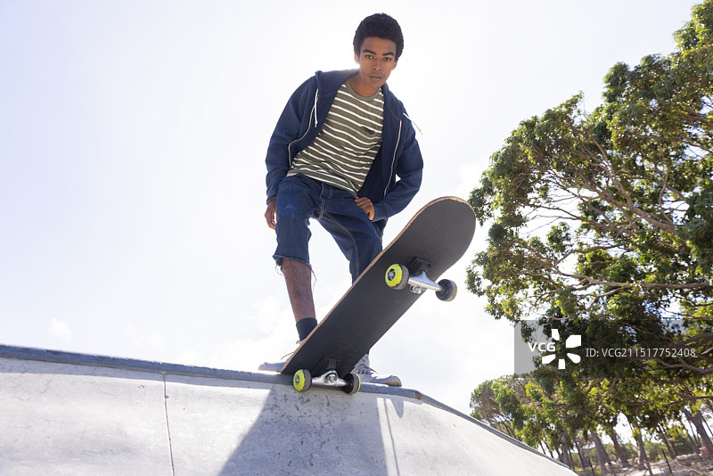 户外：玩滑板，非裔美国青少年男孩准备在坡道上滑行图片素材