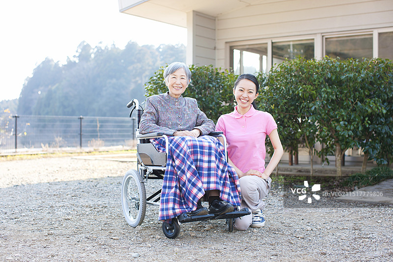 坐在轮椅上的老年妇女和她的女护理图片素材