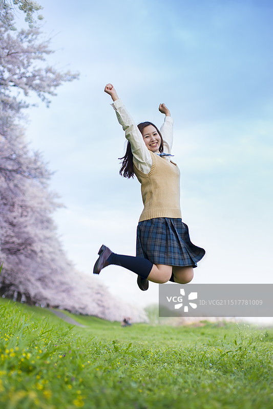 樱花树前高高跳起的女学生图片素材