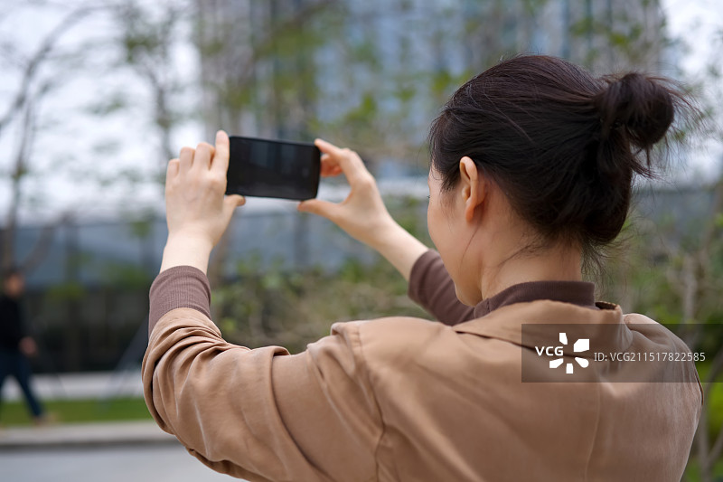 一个女人在户外用智能手机拍照图片素材