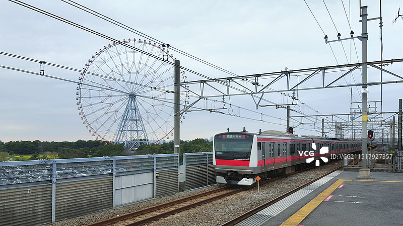 日本东京都江东区葛西临海公园站，正在通过的京叶线电车和葛西临海公园的大摩天轮图片素材