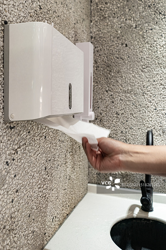 中国公共建筑设备用品拍摄主题，洗手间墙上的卫生纸，一只手正在抽餐巾盒里的纸巾，室内无人图像摄影图片素材