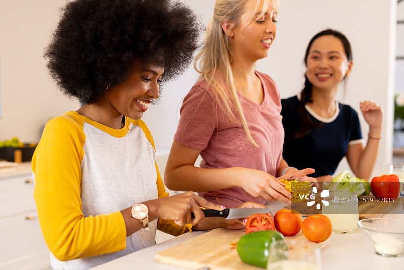 朋友们在厨房一起准备蔬菜，享受烹饪图片素材