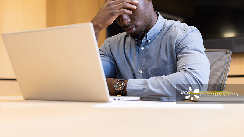 在办公桌前用笔记本电脑工作的焦虑商人图片素材