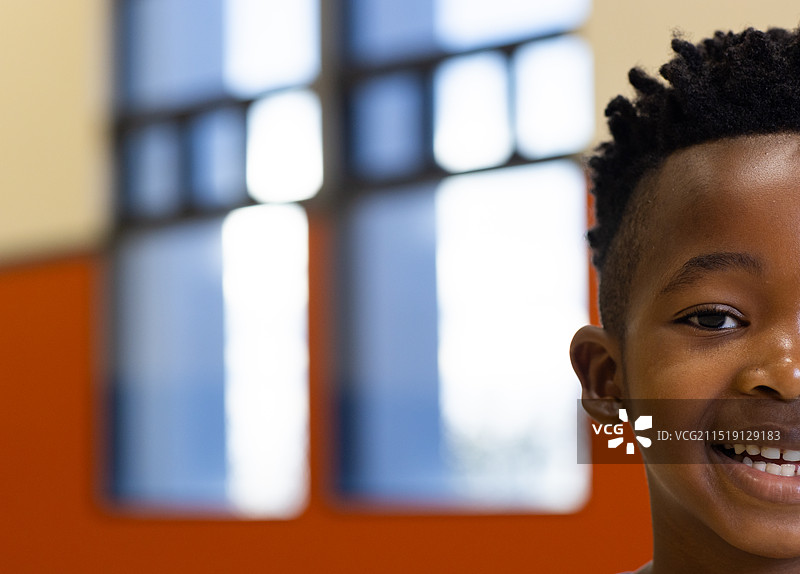 在学校体育馆里微笑的非洲裔美国男孩，背景是明亮的窗户，有复制空间图片素材