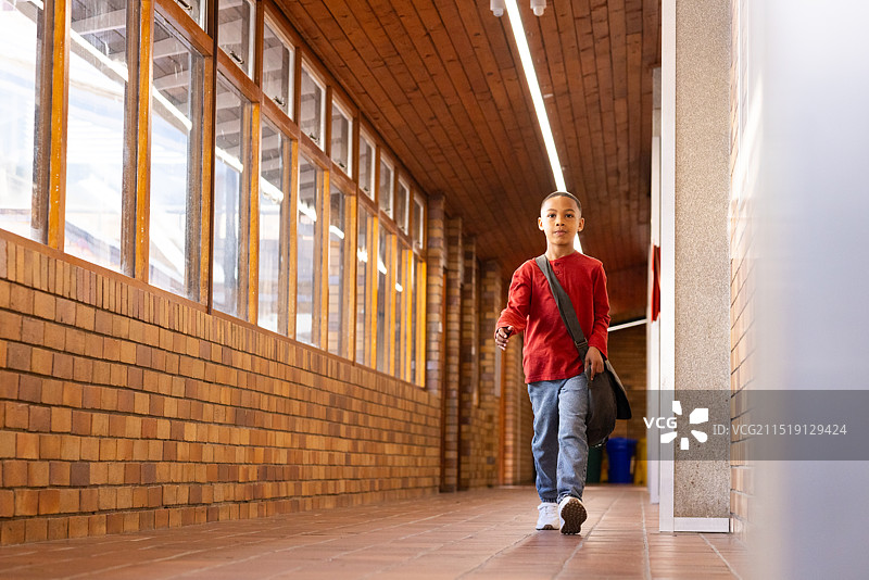 学校走廊里背书包穿红衬衫的男孩图片素材