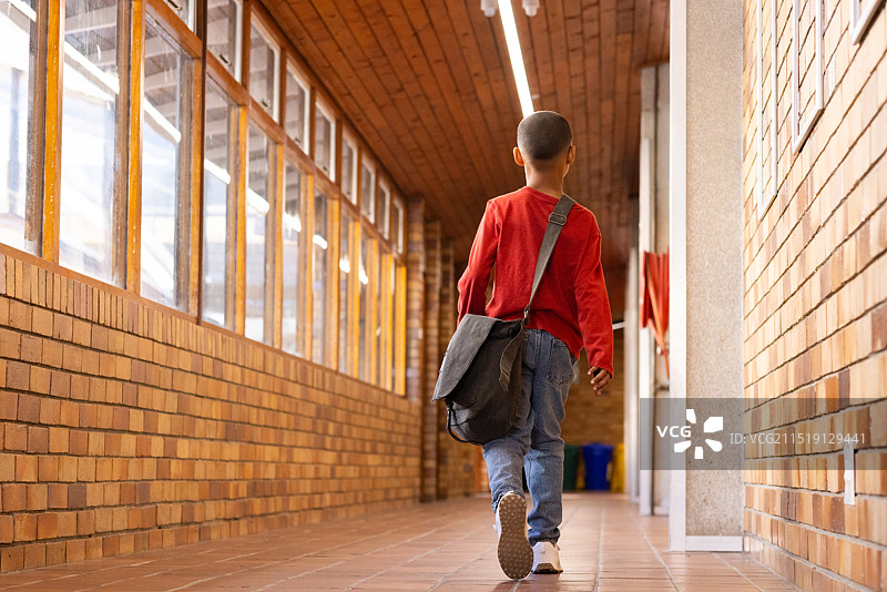 男孩背着书包走向教室走廊图片素材
