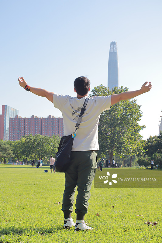 站在草坪上张开双臂的年轻男士图片素材