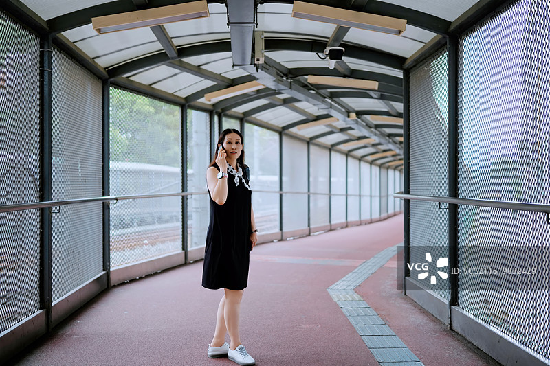 穿着黑色连衣裙的自信女人走过城市通道图片素材