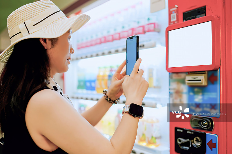 女人在自动售货机旁使用智能手机图片素材