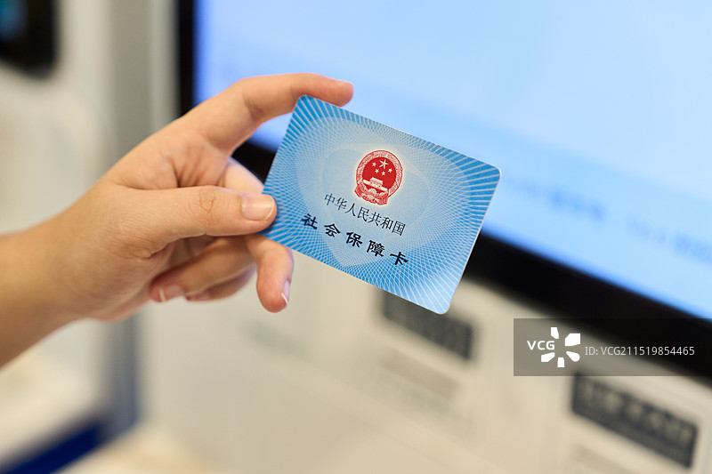 一名亚洲女子拿着社保卡在医院结算机器前图片素材