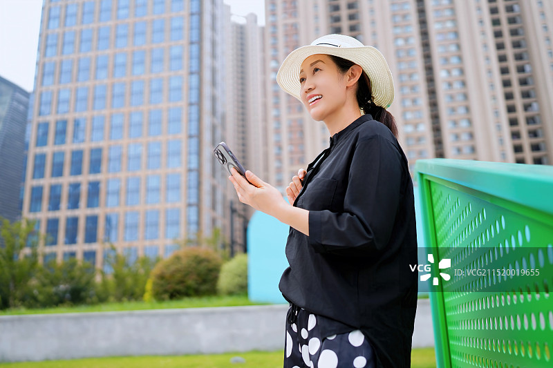 在城市街道上使用智能手机的时尚女性图片素材