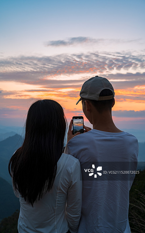 一对情侣在山顶看日落的背影图片素材