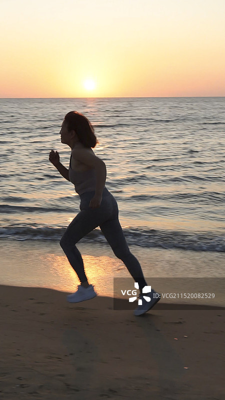 黄昏日落时分在海滩海边跑步的女人图片素材