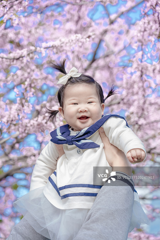 粉红色樱花树下清纯快乐迷人的女婴图片素材