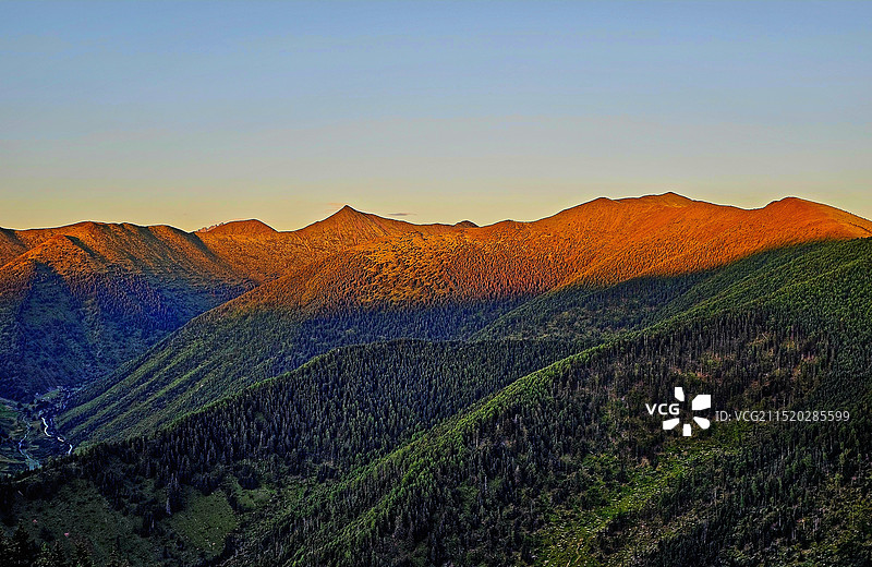 山影叠金：站在甘孜州甲根坝的山顶，欣赏到夕阳的余晖映照得更加雄伟壮丽，轮廓在暮色中显得更加分明。图片素材