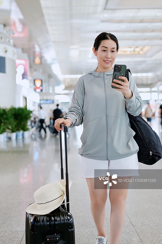 现代旅客在机场携带行李和智能手机图片素材