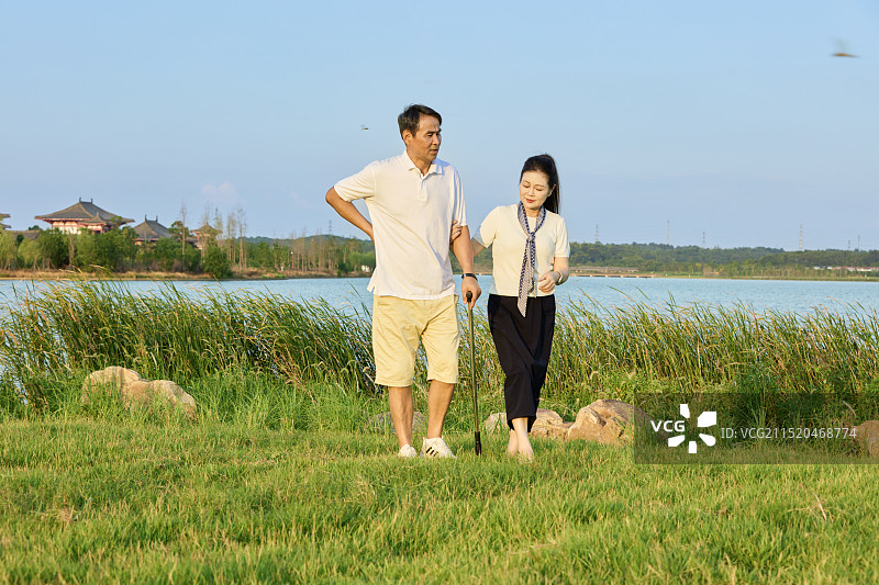 手持拐杖在湖边散步的两个老年人图片素材