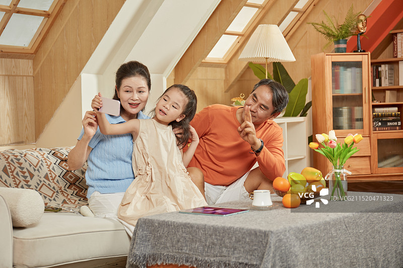 手拿手机与爷爷奶奶拍合影的小女孩图片素材