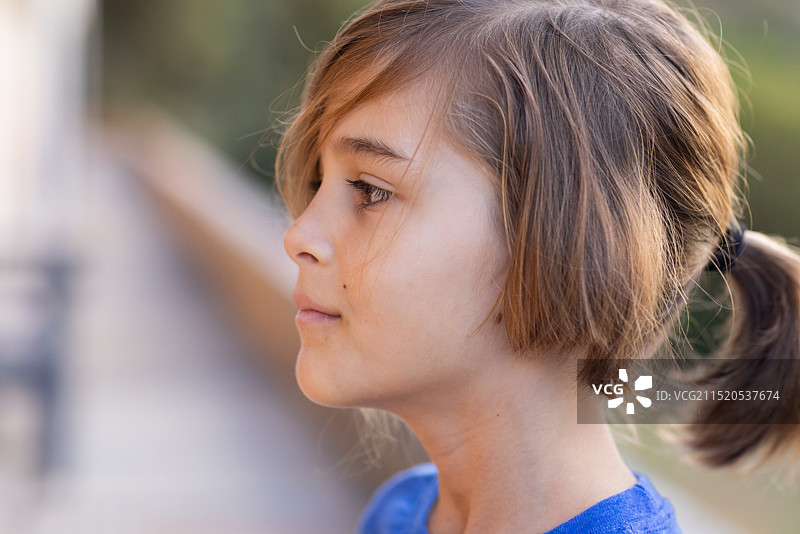 扎着马尾辫的男学生在户外沉思的侧面轮廓图片素材
