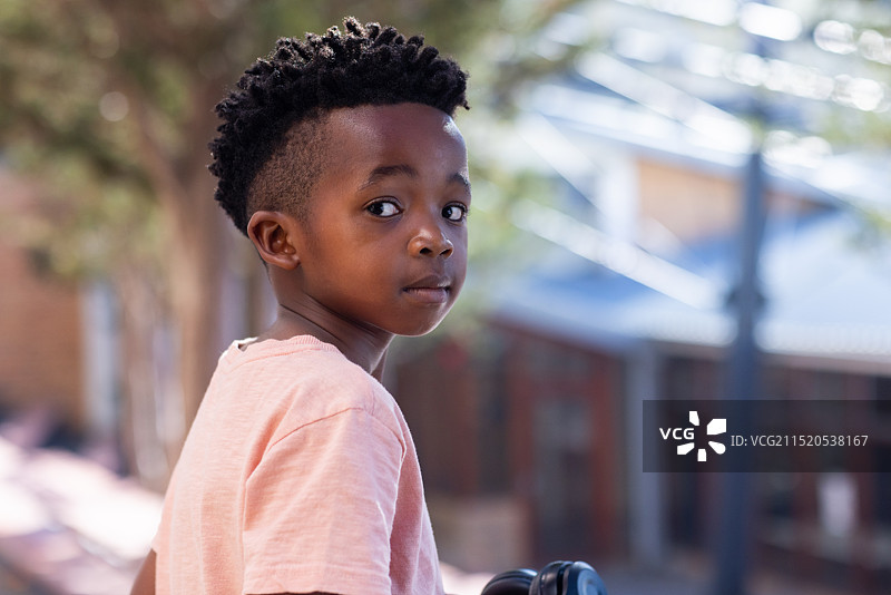 回眸：站在学校外的非洲裔美国男孩，身穿粉色衬衫图片素材