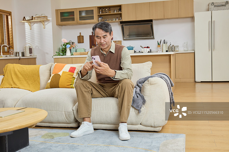 坐在客厅手拿手机的中老年男性图片素材