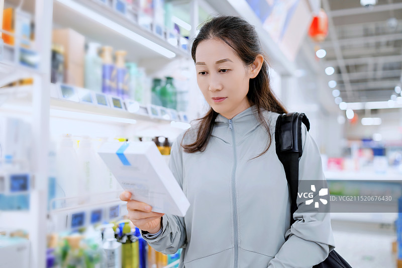 一位年轻女子在现代商店的过道里挑选商品图片素材