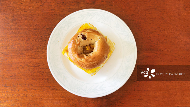 桌子上白色盘子里的一个贝果图片素材