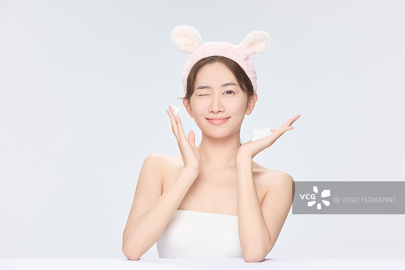 年轻漂亮的亚洲女子做皮肤保养图片素材