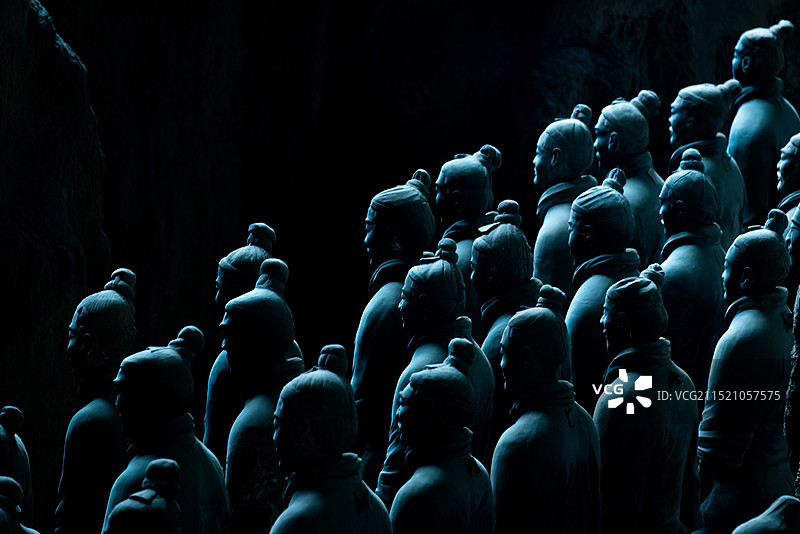 古都陕西西安秦始皇陵兵马俑是世界文化遗产，整齐排列的泥塑人俑和马匹被微弱的灯光照亮，充满神秘感远古图片素材