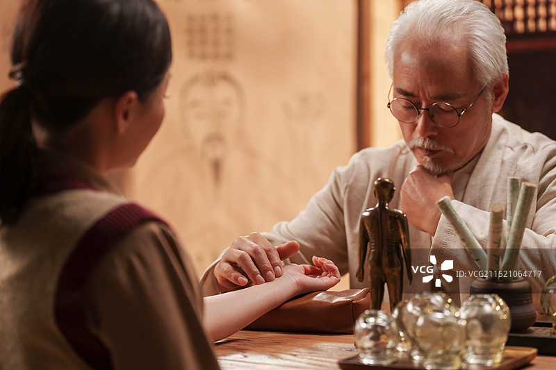 一位亚裔老年中医给患者号脉诊断病情图片素材