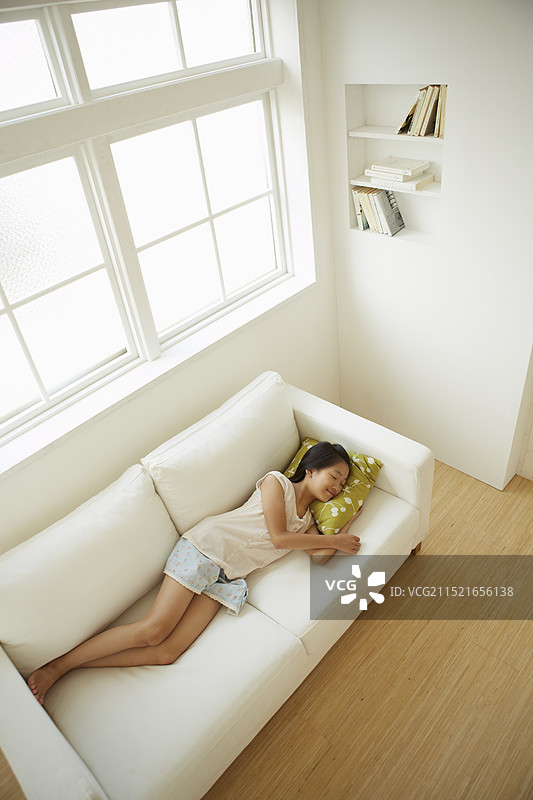 女孩躺在窗边的沙发上（俯视拍摄）图片素材