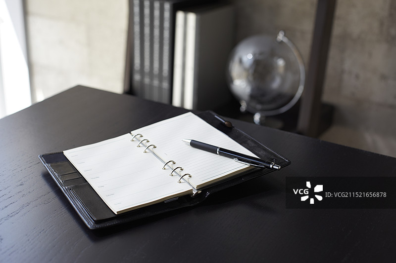 黑色桌子上的打开的笔记本和棕色书架图片素材