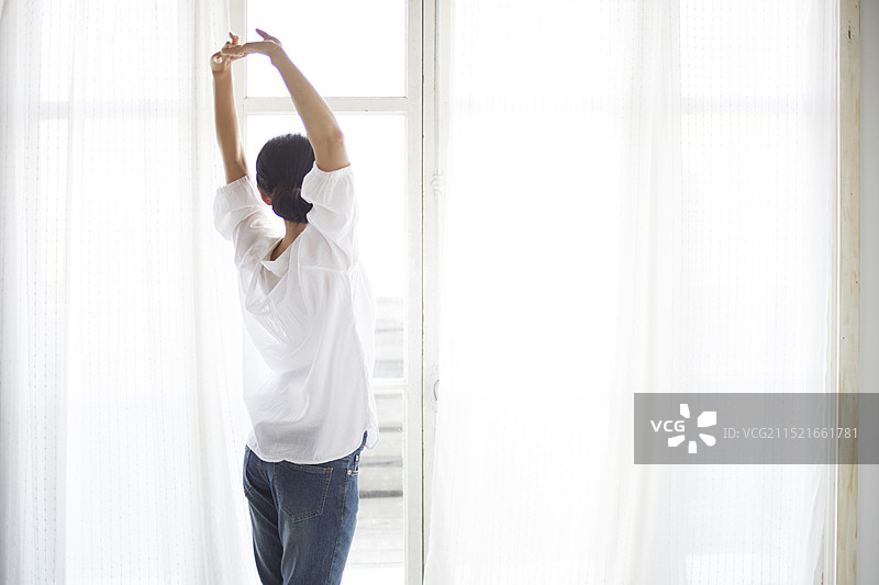 在窗边伸展身体的女人图片素材