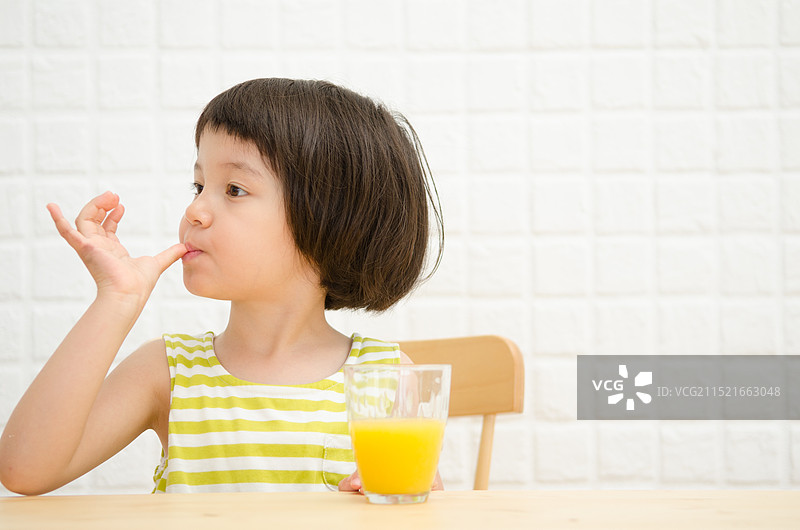 坐在椅子上舔拇指的女孩图片素材