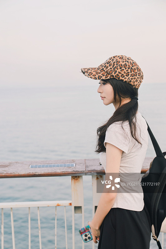站在靠海的栏杆上的年轻女子图片素材