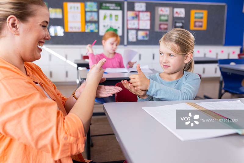 在学校教室里练习手语的女老师和学生一起微笑图片素材