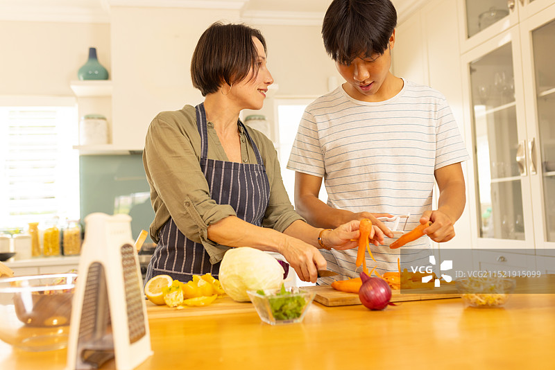 在厨房烹饪：母亲和青少年儿子一起准备蔬菜图片素材