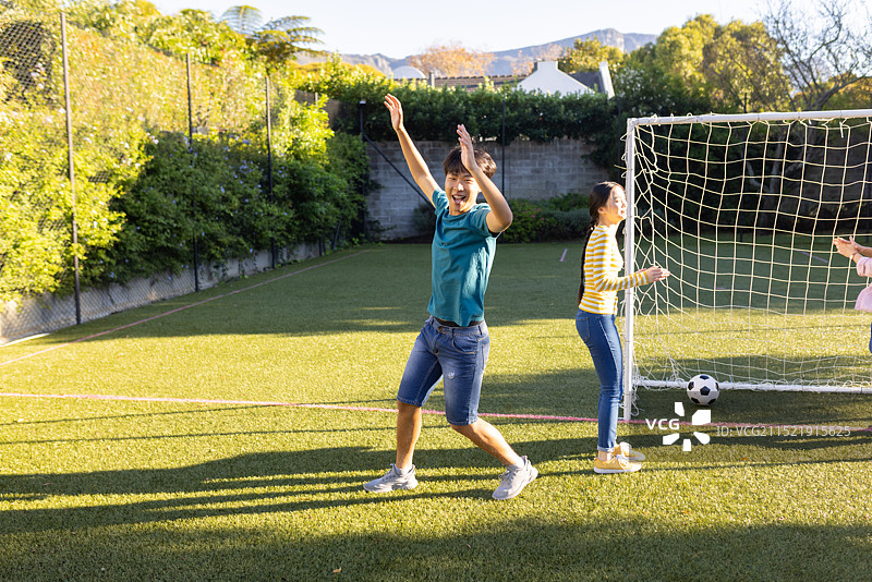 在户外球场上，男孩和朋友庆祝进球图片素材