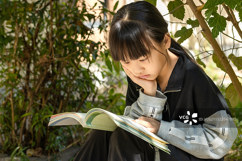坐在户外看书的亚洲小女孩图片素材