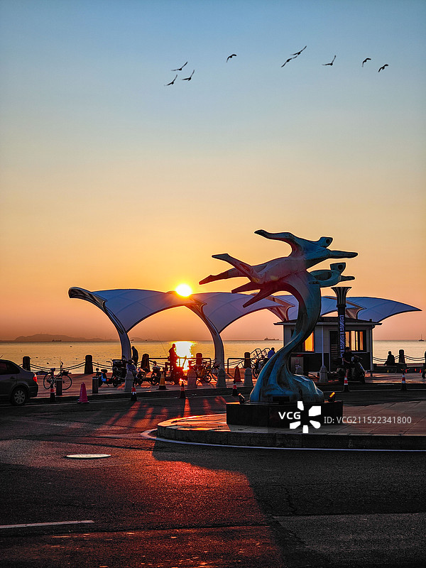 日出时海滩上的人们在天空的映衬下剪影图片素材