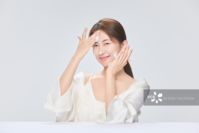 年轻漂亮的亚洲女子使用泡沫洗面奶图片素材