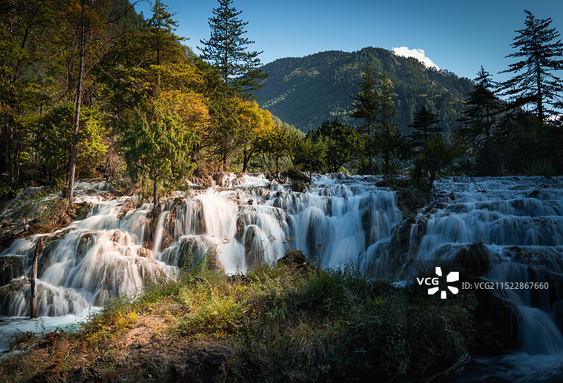 秋天森林中阳光下的瀑布图片素材