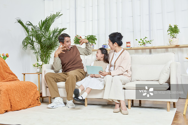 祖孙三人坐在沙发上一起看平板电脑图片素材