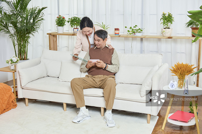 老年女性站在老年男性身后看玩手游图片素材