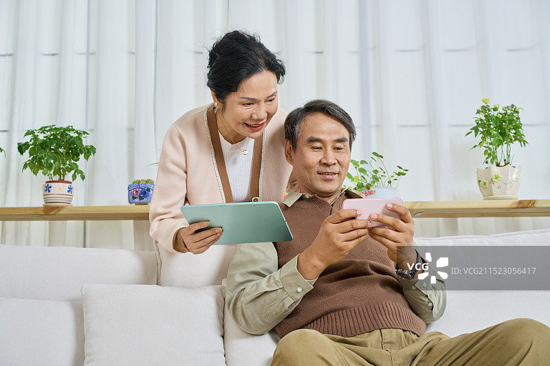 老年女性站在老年男性身后看玩手游图片素材