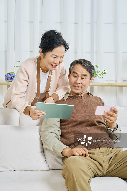 老年女性站在老年男性身后看玩手游图片素材