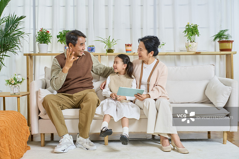 祖孙三人坐在沙发上一起看平板电脑图片素材